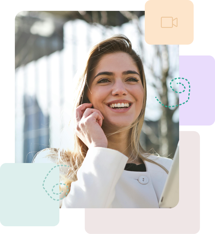 Lachende vrouw buiten in witte jas, hand tegen gezicht.